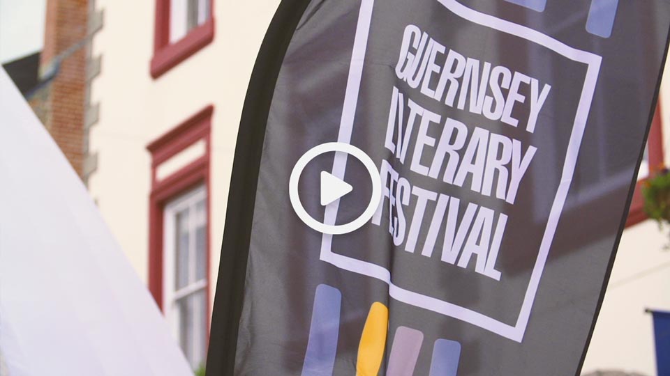 A Guernsey Literary Festival flag against a backdrop of the St.Peter Port high street